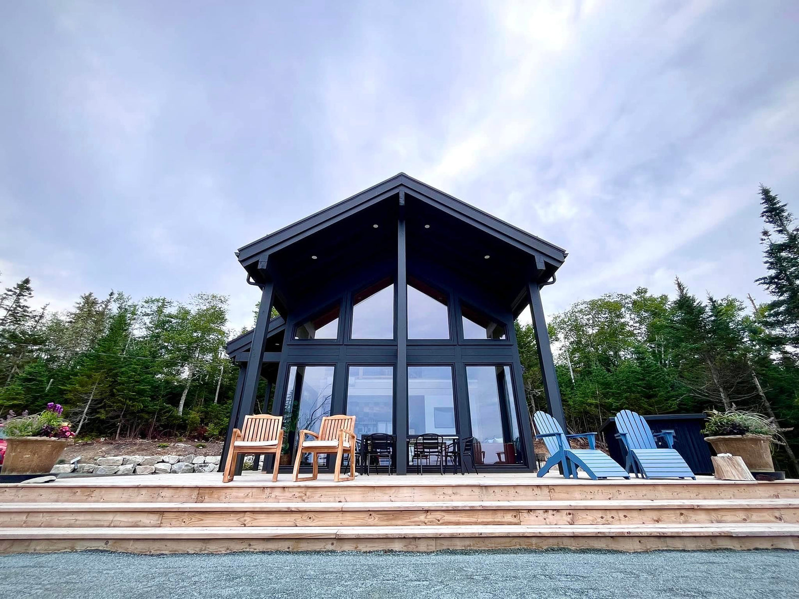 Black A-frame cabin with a wall of windows and a wide deck