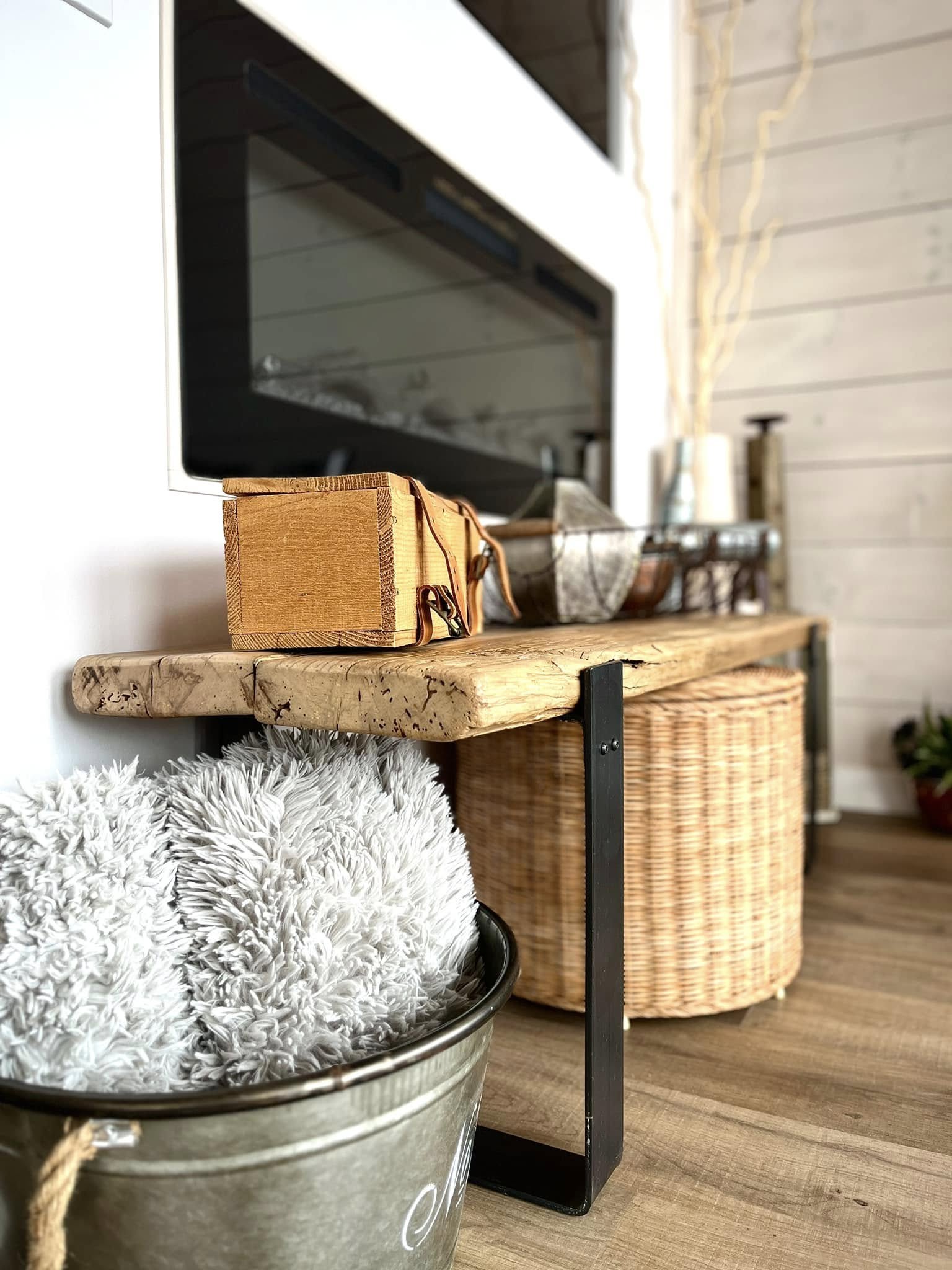 Reclaimed wood bench with baskets beside a fireplace
