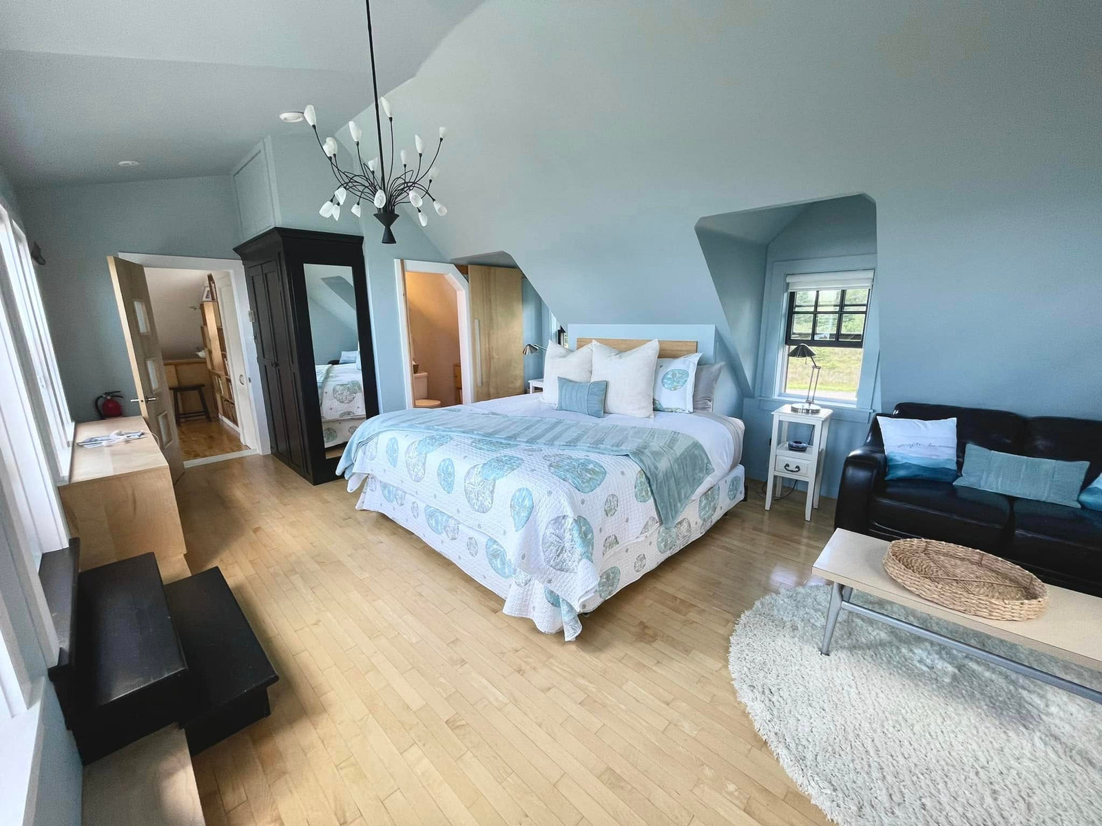 Bright blue bedroom with a made bed and hardwood floor