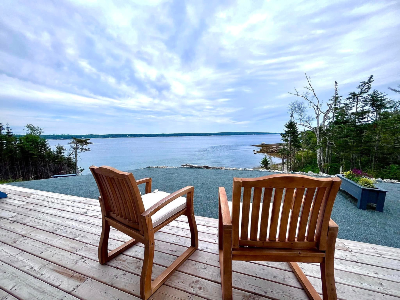 Two wooden chairs on a deck overlooking the ocean